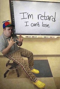 A man in a propeller beanie and Gucci tracksuit posing in front of a whiteboard that reads: I'm retard, I can't lose
